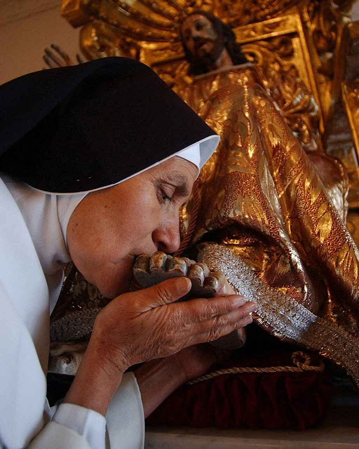 Uma religiosa do mosteiro beija os pés do Cristo das Misericórdias, no claustro do convento. Queira Ele ter pena dos maus sacerdotes e religiosos nesta época tão perturbada.