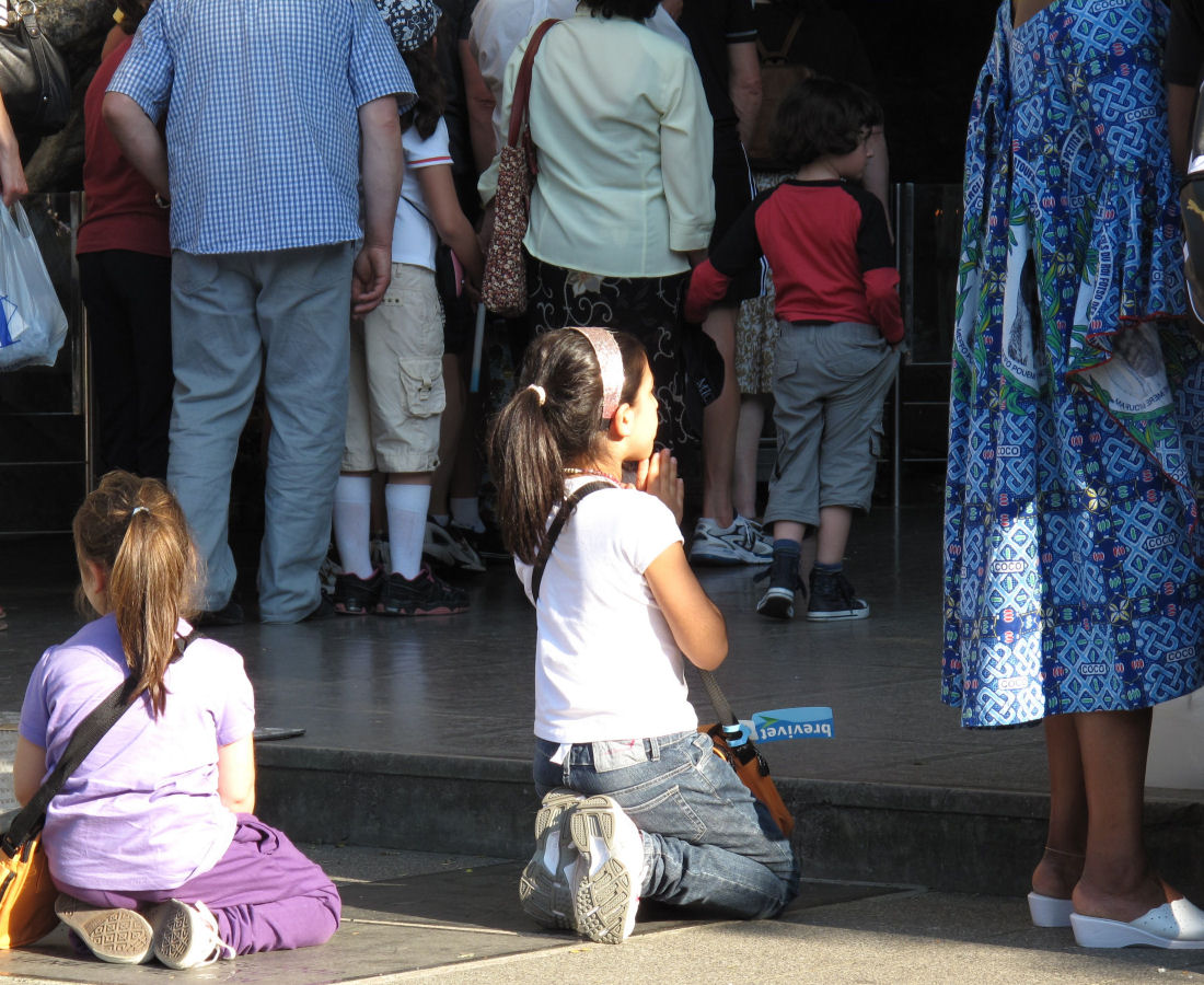 Crianças rezando diante da Gruta de Lourdes