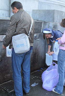 Fiéis colhem água ao pé do Santuário de Lourdes