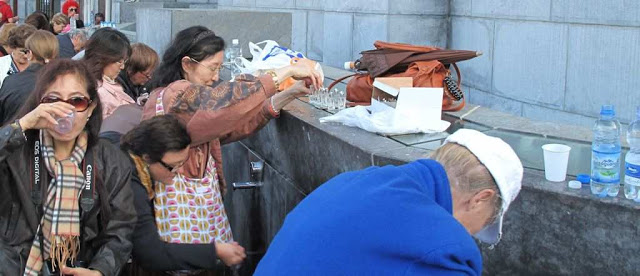 Fiéis colhem água ao pé do Santuário de Lourdes